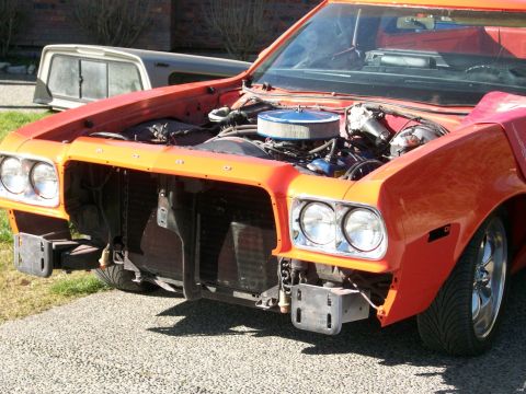 1973 Ford Ranchero - Front end of a red Ford Ranchero with the grille, hood and bumper removed, exposing the radiator, core support, bumper brackets and the hea…