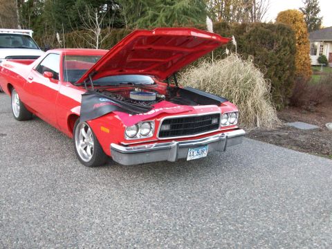 1973 Ford Ranchero - Red Ford Ranchero coupe utility parked on a driveway with its hood raised, a black fender cover draped over the front end and a chrome-topp…