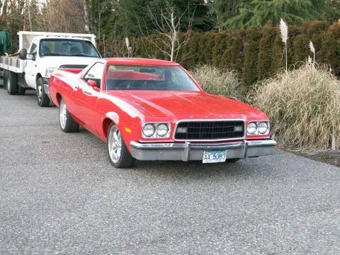1973 Ford Ranchero - A red mid-1970s Ford Ranchero coupe-utility parked on an asphalt driveway, shot from the front three-quarter. It has quad headlights in a b…