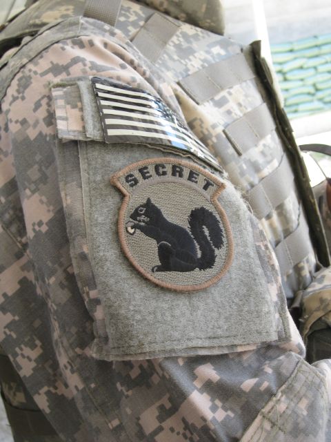 2003 Jeep TJ - A close-up of a US Army uniform sleeve displays an American flag patch and a circular patch with the word 'SECRET' above a black squirrel h…