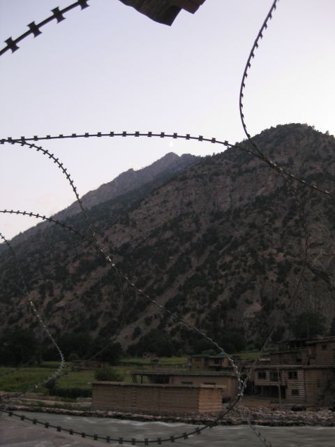 2003 Jeep TJ - A view of a mountainous region with buildings and a river, partially obscured by barbed wire.