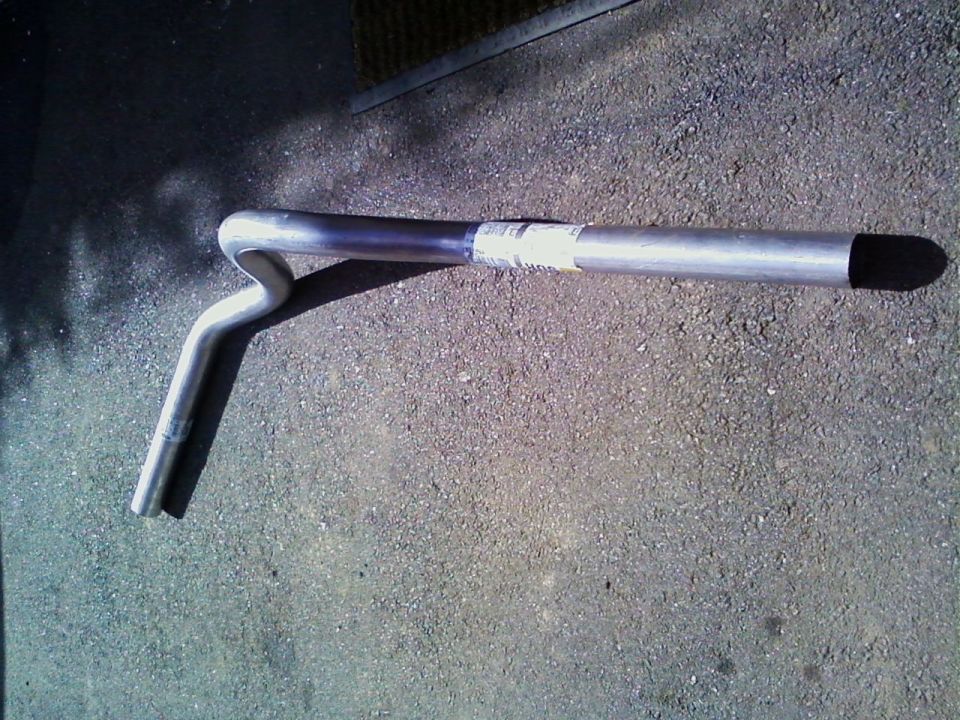 Bent metal handlebar or tubular bracket lying on a gravel surface