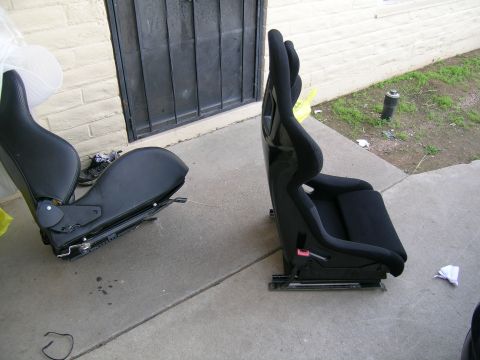 1995 Ford Probe - Two racing seats are shown outside, one with a glossy black finish and the other with a matte black finish.