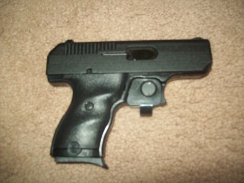 1985 Ford Bronco - A black handgun rests on a carpeted surface, showing its side profile and grip detail.