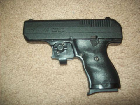 1985 Ford Bronco - A black handgun is shown resting on a carpeted surface. Text is visible on the slide of the firearm.