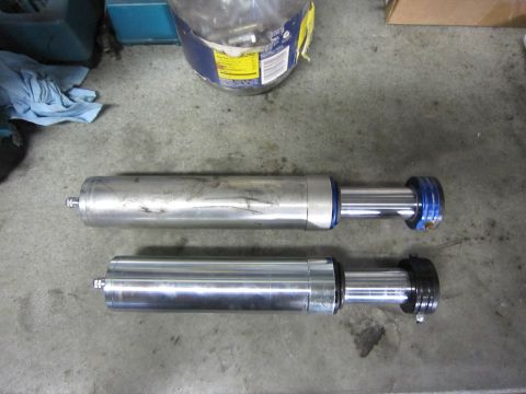 1996 Ford Bronco - Two shock absorbers are laid out on a concrete floor, possibly for installation or repair.