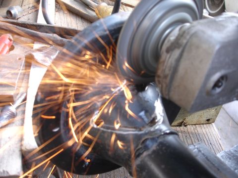 1995 Ford Taurus - A close-up shows a metal automotive part being ground, with numerous sparks flying.