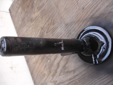 1995 Ford Taurus - A black suspension component is shown against a wooden background. The part appears to be a strut or shock absorber assembly.