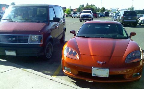 2006 Ford E350 - An orange sports car and a maroon van are parked in a lot.