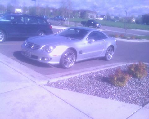 2006 Ford E350 - A silver convertible sports car is parked in a lot next to a dark SUV.