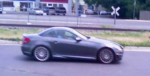 2006 Ford E350 - A gray Mercedes-Benz SLK-Class convertible is seen driving on a road next to railroad tracks.