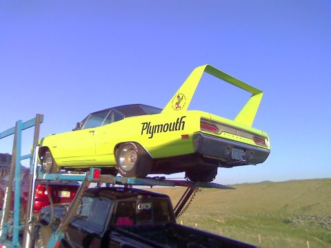 2006 Ford E350 - A lime green 1970 Plymouth Superbird is loaded onto a car carrier, its distinctive rear wing prominent against the blue sky.
