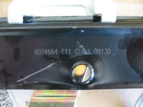 2003 Ford Crown Victoria - A close-up view of a black metal automotive part with manufacturing codes stamped on its surface.