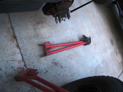 1986 Ford Bronco - Vehicle suspension parts, including control arms and a brake assembly, lie on a concrete floor.