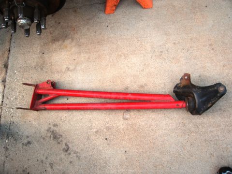 1986 Ford Bronco - A red radius arm assembly is shown laid out on a concrete surface.