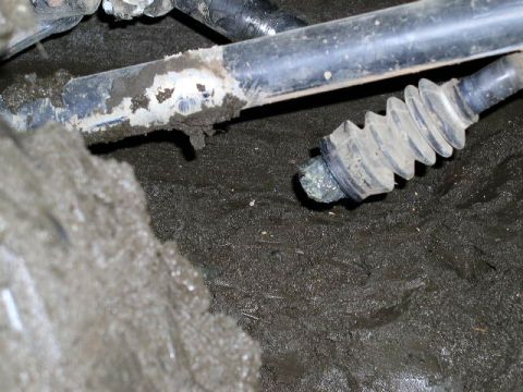 1979 Ford Bronco - Close-up view of a muddy undercarriage component, a rubber boot and exposed metal rod.