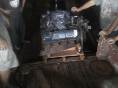 1986 Ford Bronco - A blue Ford engine is being moved on a pallet, with several people around it.