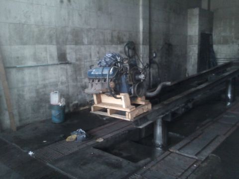 1986 Ford Bronco - A V8 engine is displayed on a wooden pallet in a workshop setting.