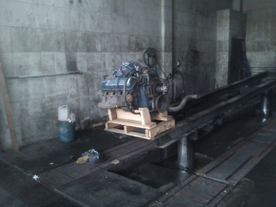 V8 engine sitting on a wooden pallet in a garage