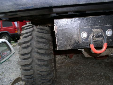 1979 Ford Bronco - This photo shows the undercarriage of a vehicle, focusing on its tire and a heavy-duty tow hook. Another vehicle is parked nearby.