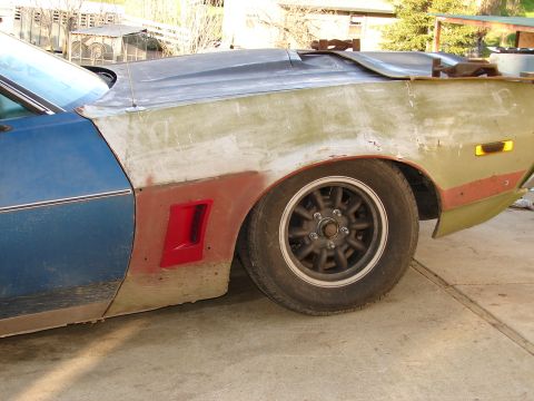 1973 Ford Ranchero - A side view of a 1973 Ford Ranchero undergoing bodywork, showing primer, blue paint, and a red vent detail.