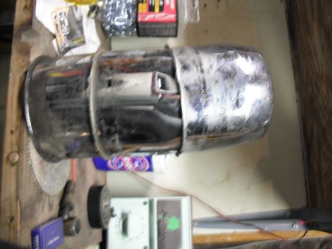 1991 Ford Bronco - A chrome exhaust pipe, likely from a vehicle, sits on a workbench with various tools and supplies.