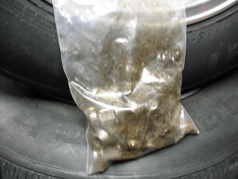 1991 Ford Bronco - A plastic bag filled with metal parts sits on top of two tires.