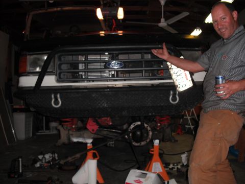 1991 Ford Bronco - A man stands next to the front of a 1991 Ford Bronco, which is elevated on jack stands for maintenance.