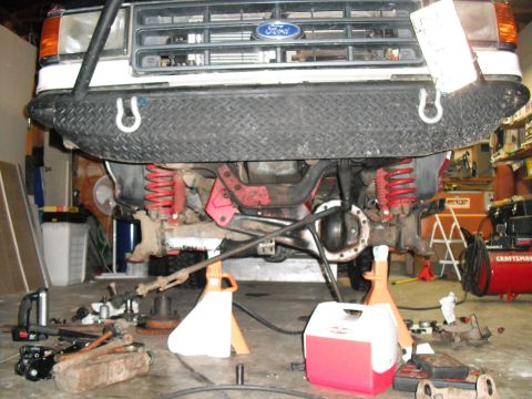 1991 Ford Bronco - Front suspension and differential of a 1991 Ford Bronco undergoing maintenance in a garage.