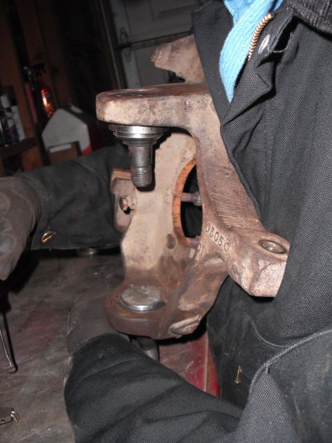 1991 Ford Bronco - A person works on a vehicle's ball joint and axle pivot mount bushing in a garage.