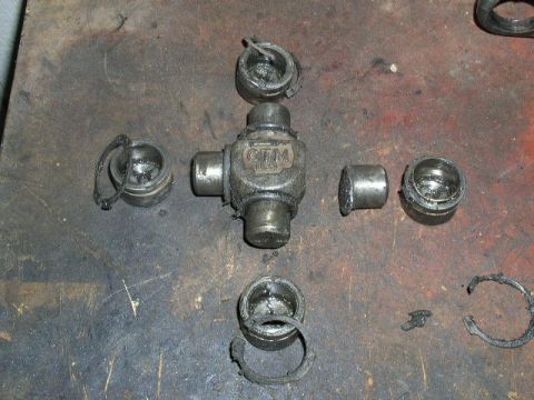 1979 Ford Bronco - A disassembled universal joint lies on a dirty workbench, showing its component parts and signs of wear.
