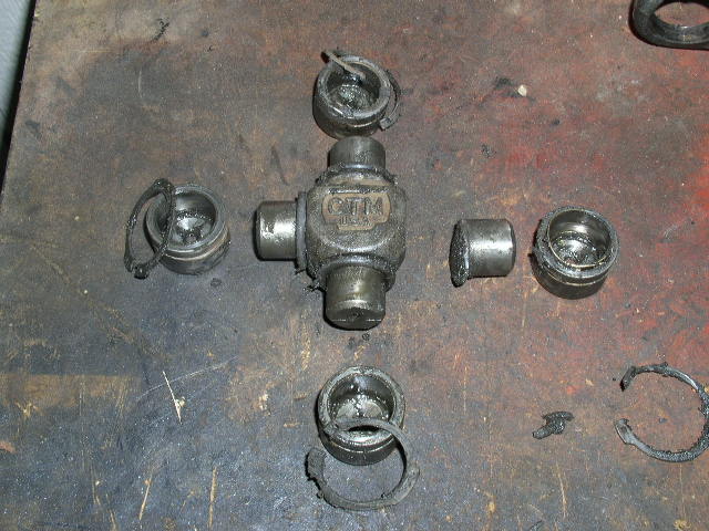 Disassembled universal joint with grease and metal shavings on a workbench