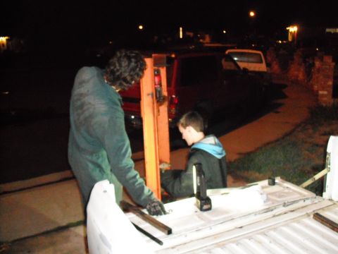 1991 Ford Bronco - Two people are working on a vehicle part at night, with other vehicles in the background.