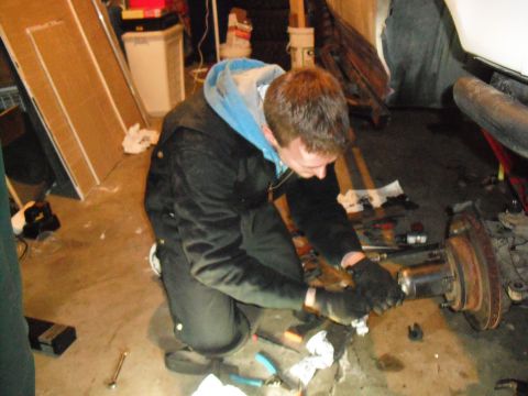 1991 Ford Bronco - A person works on the axle assembly of a 1991 Ford Bronco in a garage setting.