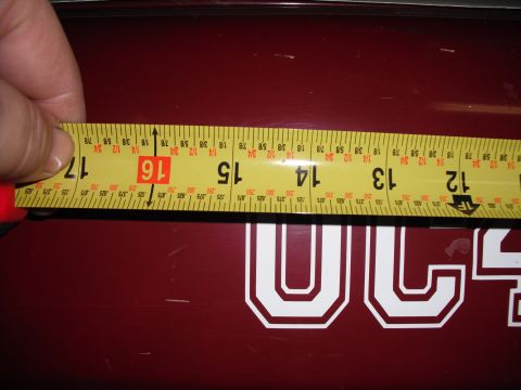 1991 Ford Bronco - A measuring tape is held over a maroon surface displaying white lettering, likely part of a vehicle decal.