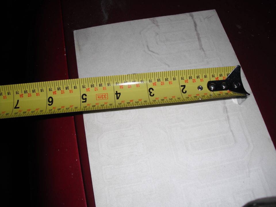 Yellow measuring tape on a white sticker with faint block lettering