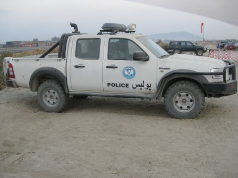 2003 Jeep Wrangler - A white Ford Ranger pickup truck with police markings is parked on a dirt surface.