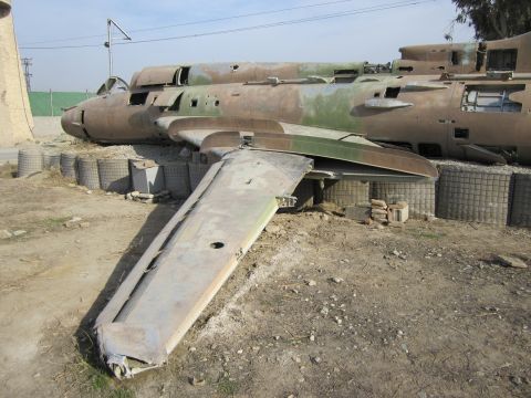 2003 Jeep Wrangler - Damaged aircraft fuselage and wing section in a sandy, outdoor location.
