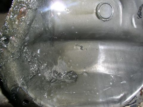 1979 Ford Bronco - This differential cover shows significant damage, likely from impact, with metal fragments and fluid present.