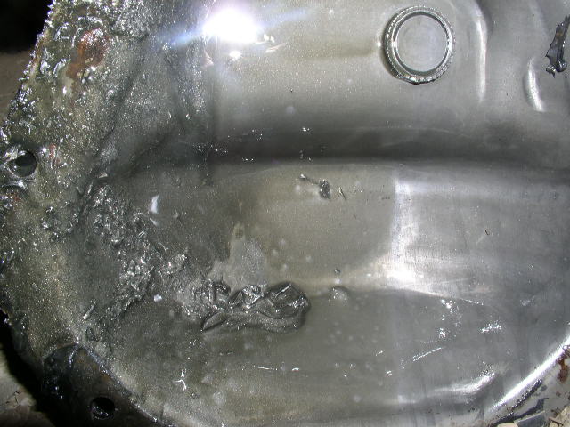 Close-up of a heavily damaged metal differential cover with debris and fluid