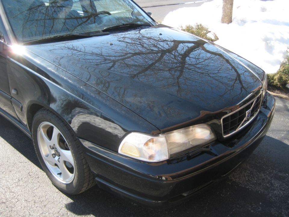 Black Volvo sedan front corner, showing grille and headlight