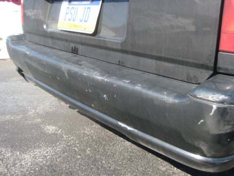 1993 Ford Probe - The rear bumper of a dark SUV shows significant scuffing and wear.