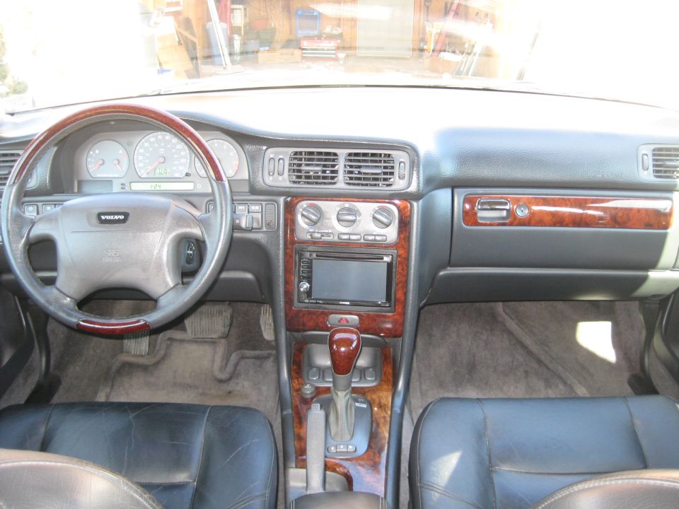 Interior shot of a Volvo with wood trim, leather seats, and an aftermarket stereo