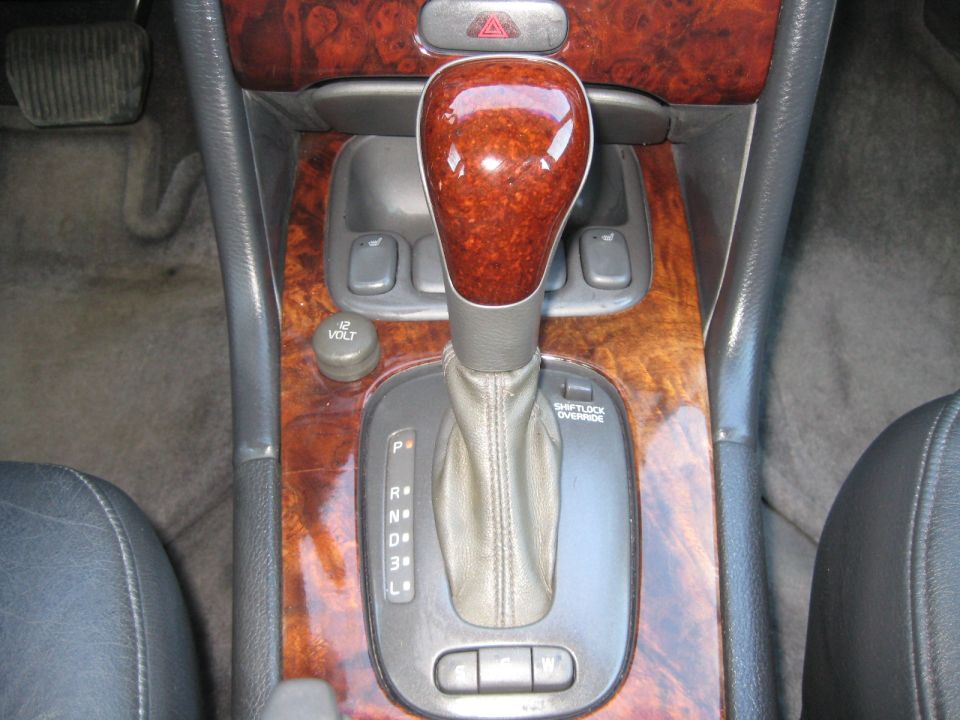 Car interior showing automatic transmission shifter, wood trim, and 12V power outlet