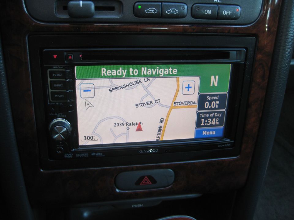 Car interior dashboard with Kenwood navigation screen displaying map