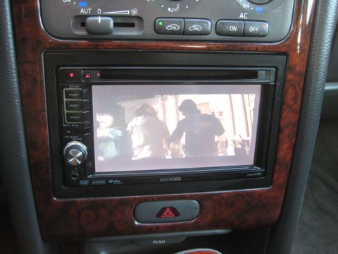 1993 Ford Probe - Infotainment screen in a car interior displays video content, surrounded by wood grain trim and climate controls.