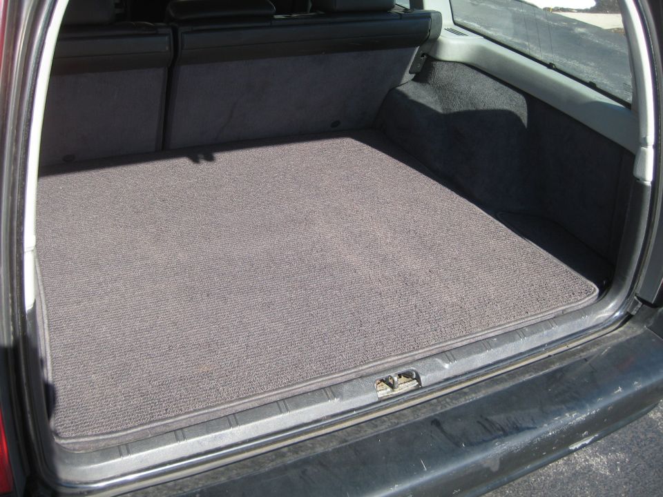 Trunk interior with gray carpet mat and folded rear seats