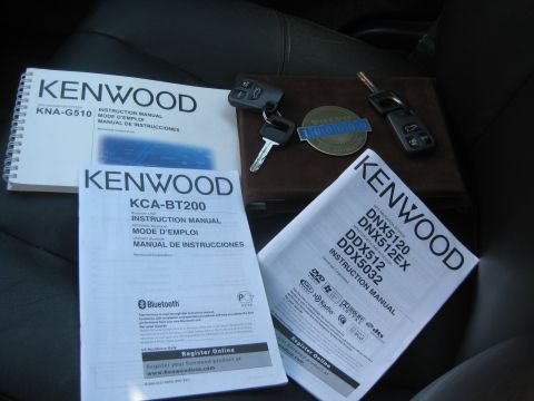 1993 Ford Probe - Car interior displays multiple Kenwood instruction manuals and car keys, suggesting an audio system upgrade or documentation.