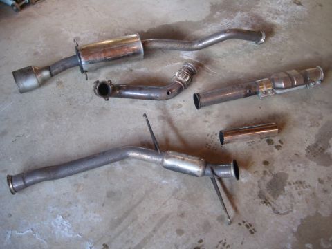 1993 Ford Probe - Multiple exhaust system components, including a muffler and catalytic converter, are displayed on a concrete surface.