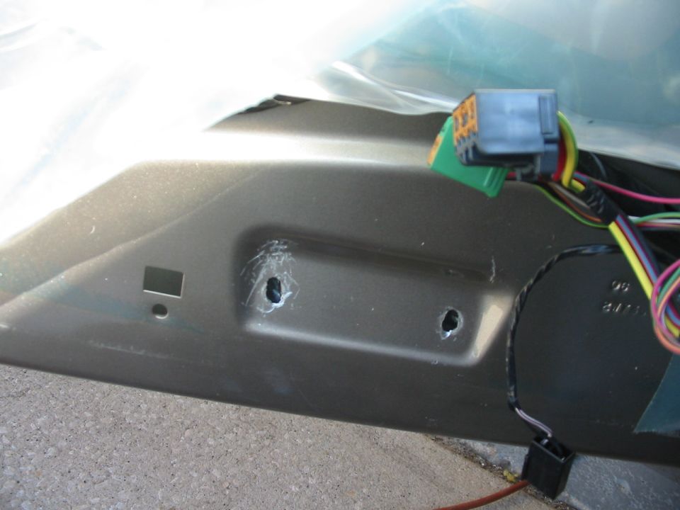 Close-up of car door interior showing wiring harness and connector, with two mounting holes